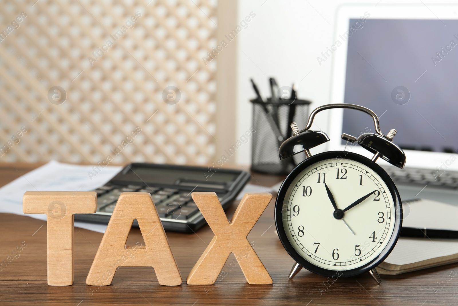 Photo of Word Tax made of wooden letters and alarm clock on table