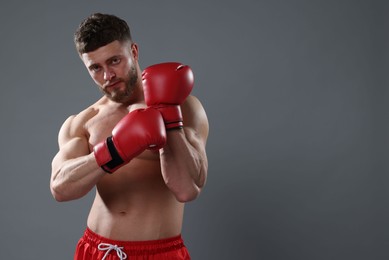 Photo of Man putting on boxing gloves against grey background. Space for text