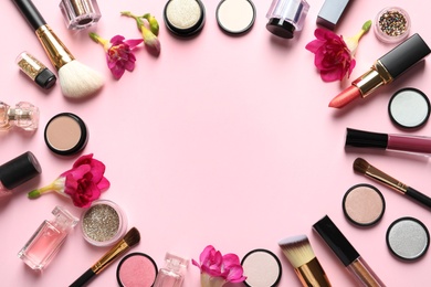 Photo of Frame made of different makeup products and flowers on color background. Space for text