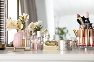 Photo of Luxury makeup products and accessories with perfumes on dressing table