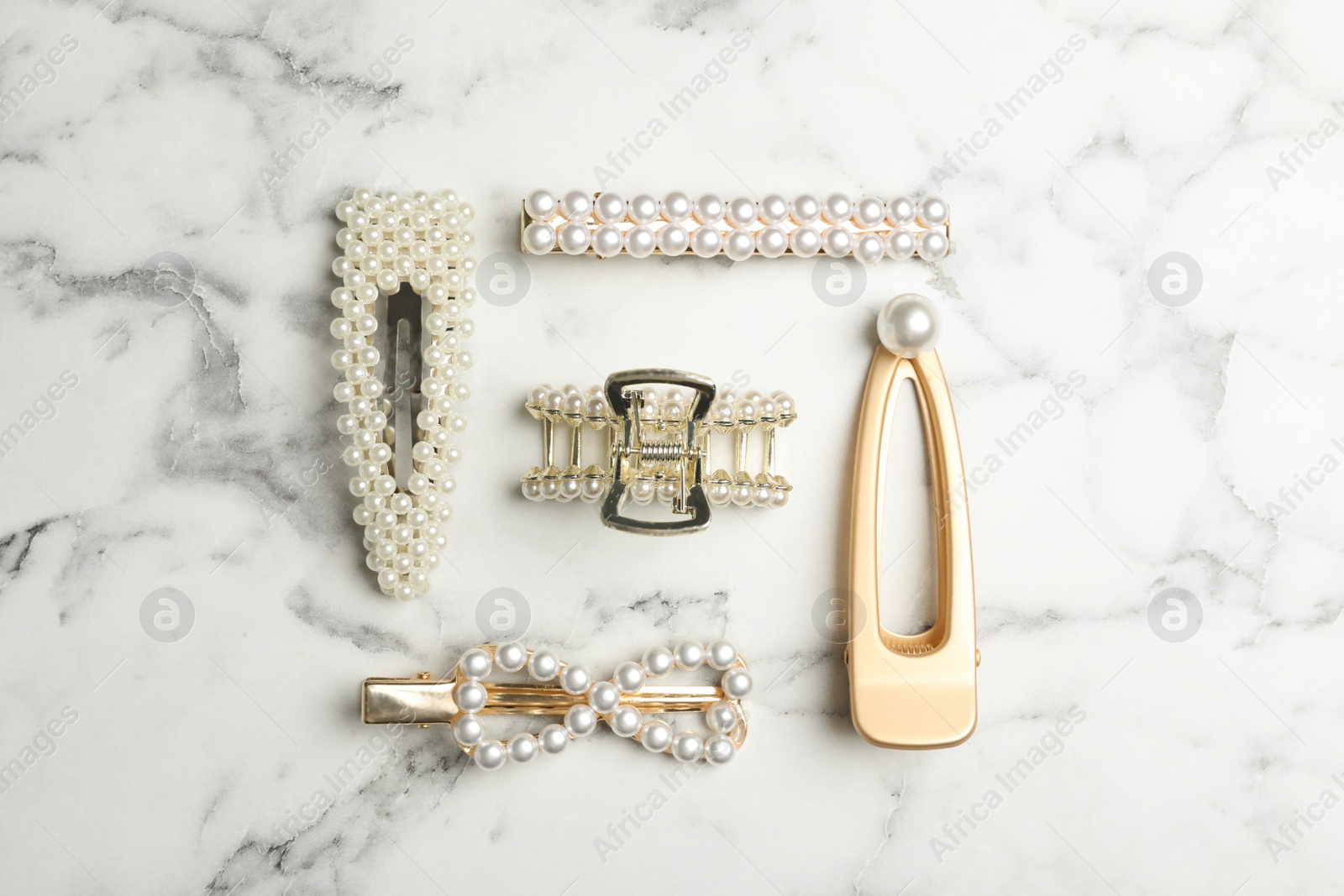 Photo of Stylish hair clips on white marble table, flat lay