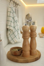Photo of Wooden salt and pepper shakers, bowl with bay leaves on white countertop in kitchen