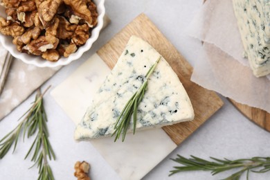 Tasty blue cheese with rosemary and walnuts on light table, flat lay