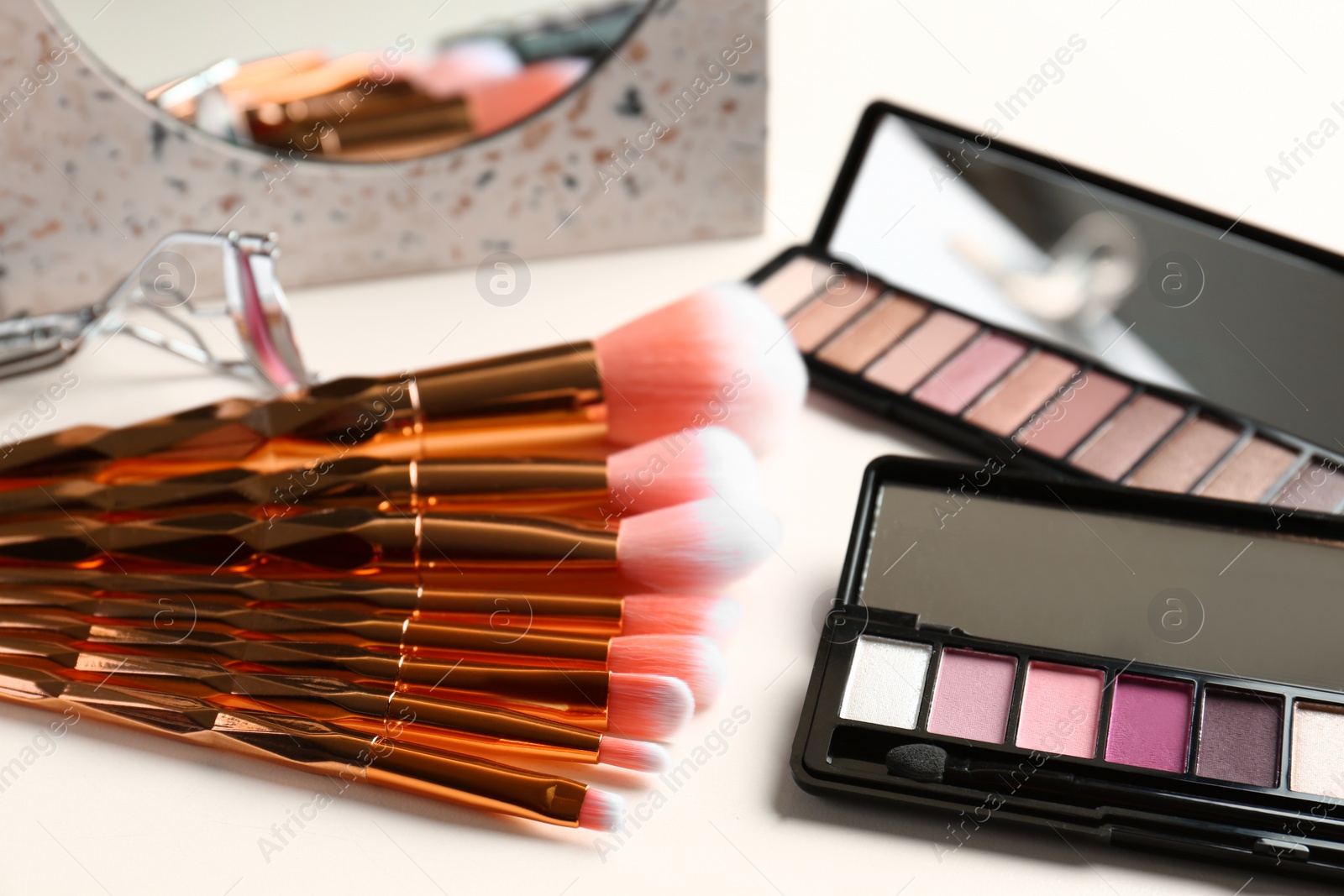 Photo of Set of makeup brushes and eye shadow palette on table
