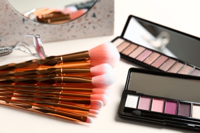 Photo of Set of makeup brushes and eye shadow palette on table