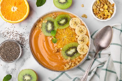 Bowl of delicious fruit smoothie with fresh banana, kiwi slices and granola served on white marble table, flat lay