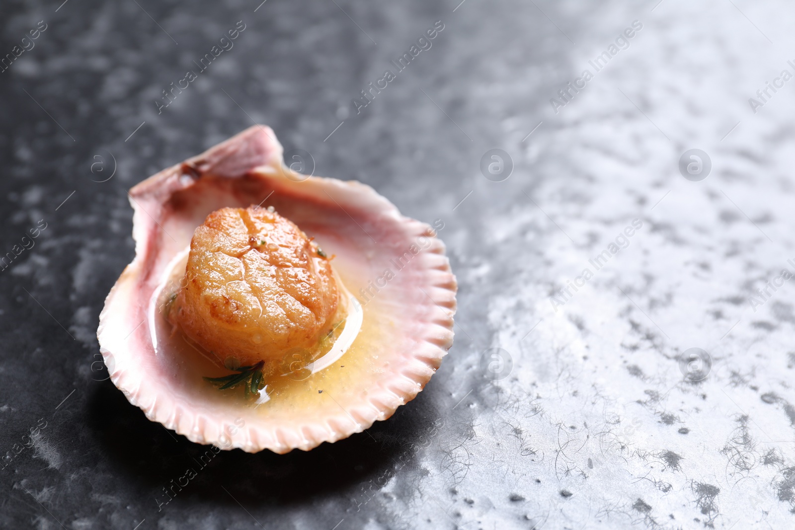 Photo of Delicious fried scallop in shell on black table. Space for text