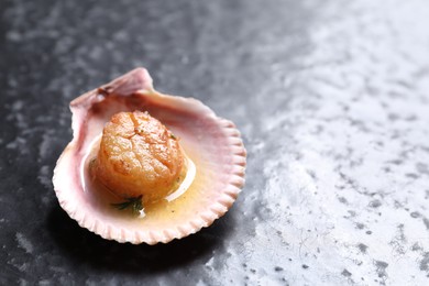 Photo of Delicious fried scallop in shell on black table. Space for text