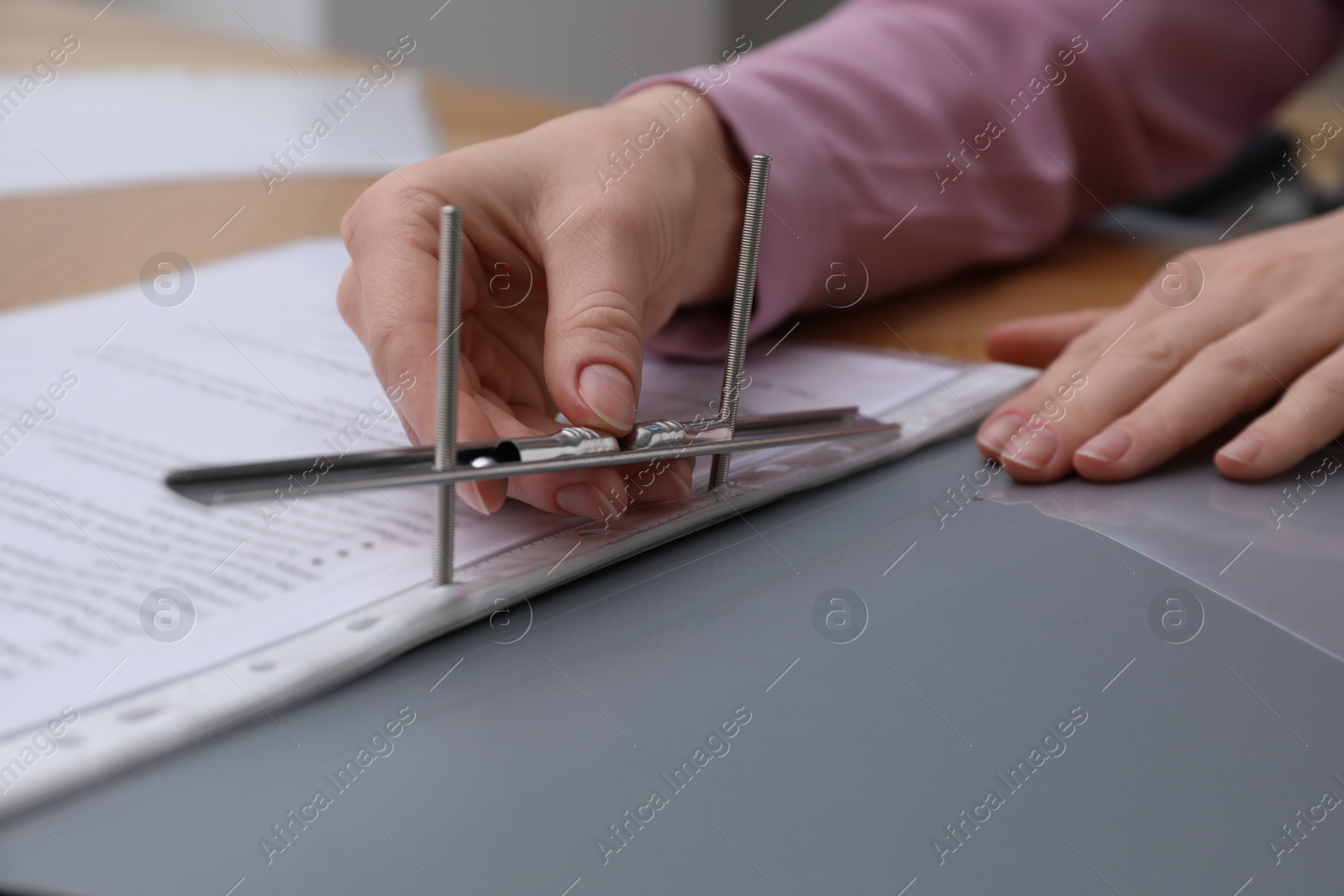 Photo of Woman fixing folder with punched pockets at table, closeup