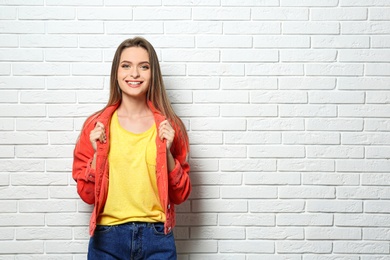 Photo of Young woman wearing blank t-shirt near white brick wall. Mockup for design