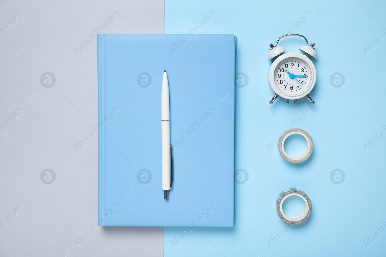 Photo of Light blue notebook, alarm clock and tapes on color background, flat lay