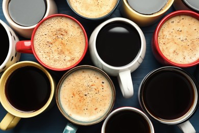 Many cups of different coffee drinks on blue table, flat lay