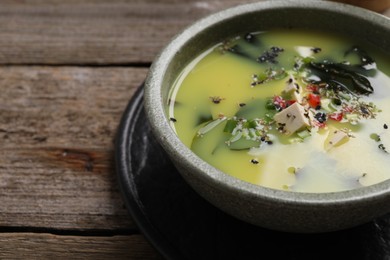 Photo of Bowl of delicious miso soup with tofu on wooden table, closeup. Space for text