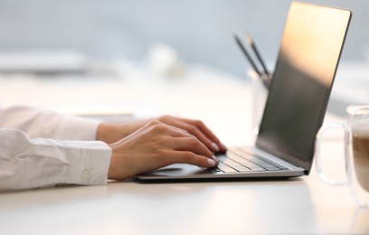 Photo of Woman using modern laptop at white desk, closeup