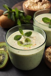 Photo of Glass of tasty kiwi smoothie with oatmeal on dark table