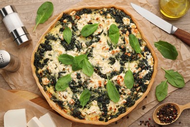 Photo of Delicious homemade spinach quiche and ingredients on table, flat lay