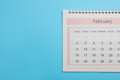 Photo of February calendar on light blue background, top view. Space for text