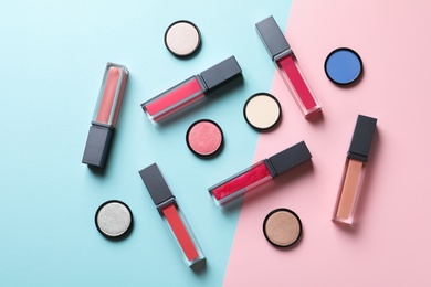Photo of Composition of lipsticks and eyeshadows on color background, flat lay