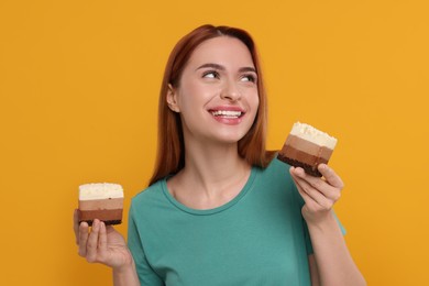 Young woman with pieces of tasty cake on orange background