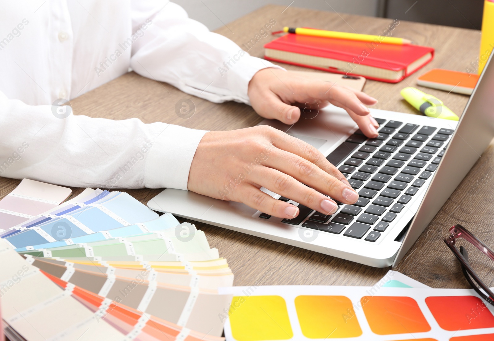 Photo of Woman working with laptop and palette samples at wooden table, closeup