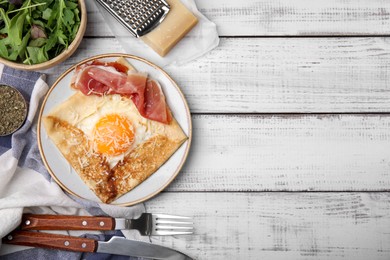 Delicious crepe with egg served on white wooden table, flat lay with space for text. Breton galette