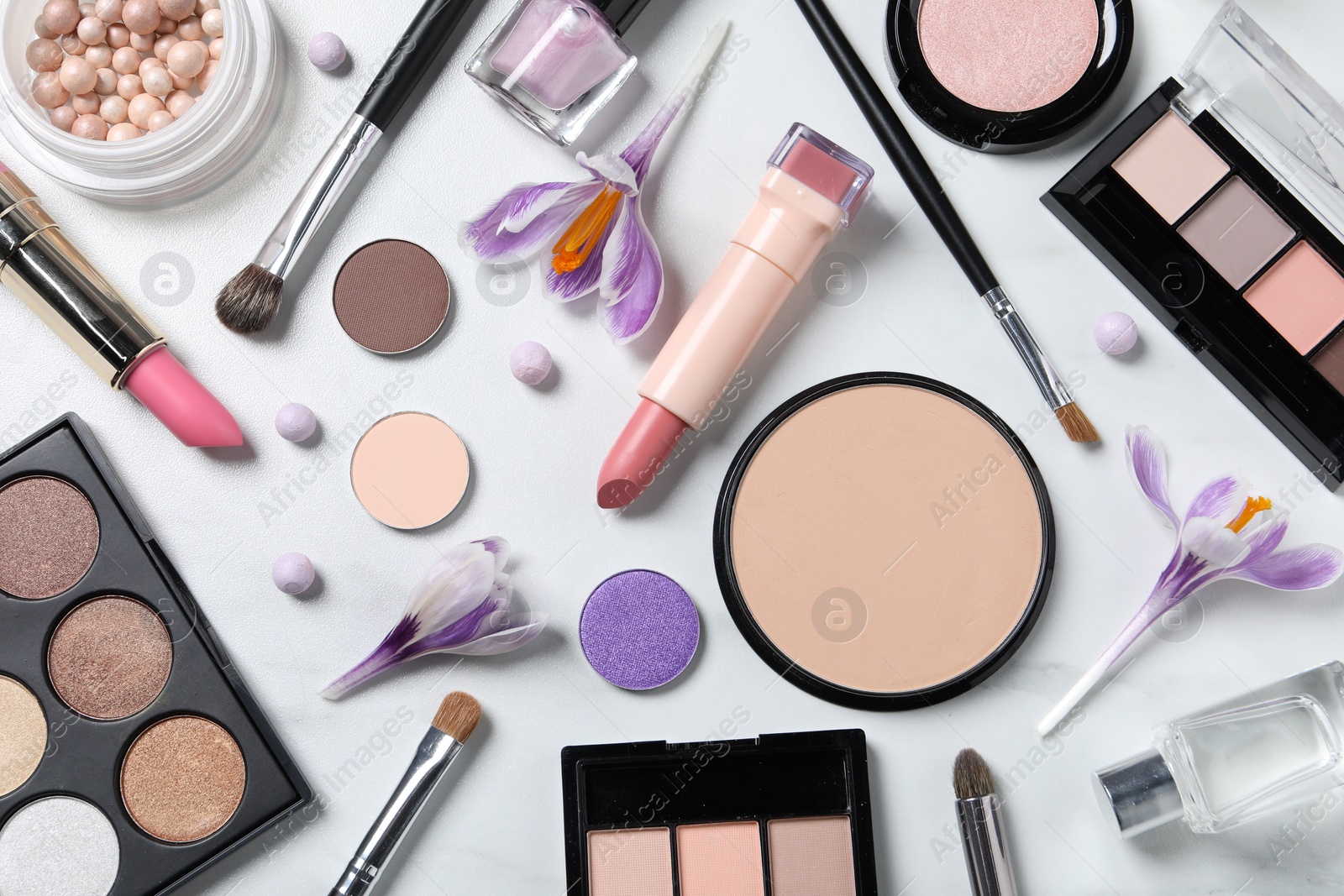 Photo of Flat lay composition with different makeup products and beautiful crocuses on white marble table