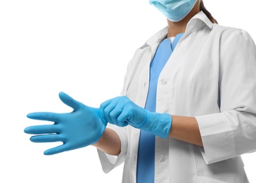Doctor in protective mask putting on medical gloves against white background, closeup