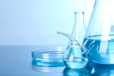 Photo of Laboratory glassware with liquid on table, space for text. Solution chemistry