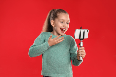 Excited little blogger recording video on red background