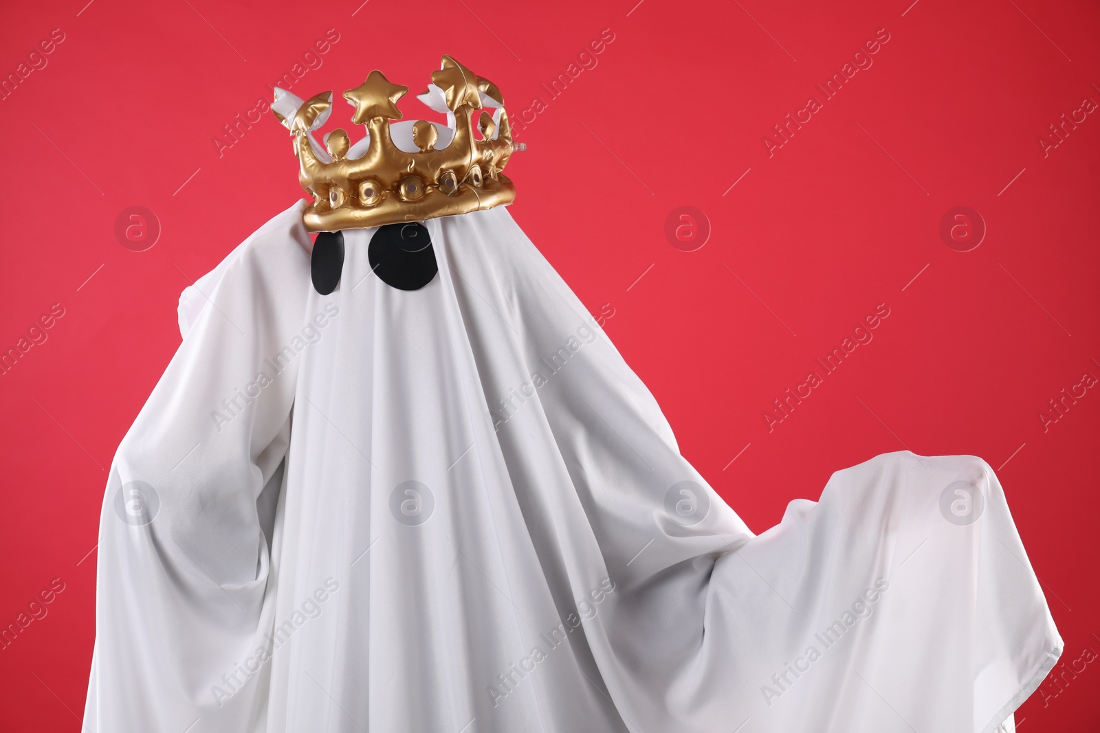 Photo of Person in ghost costume and luxurious crown on red background