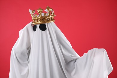 Photo of Person in ghost costume and luxurious crown on red background