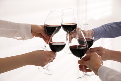 People clinking glasses of wine on white background, closeup