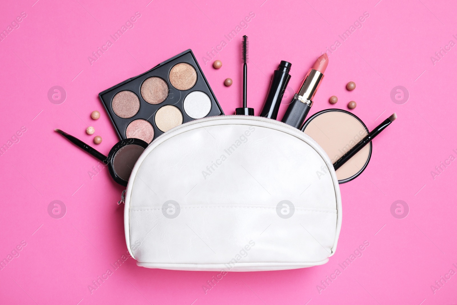 Photo of Cosmetic bag with makeup products and accessories on pink background, flat lay
