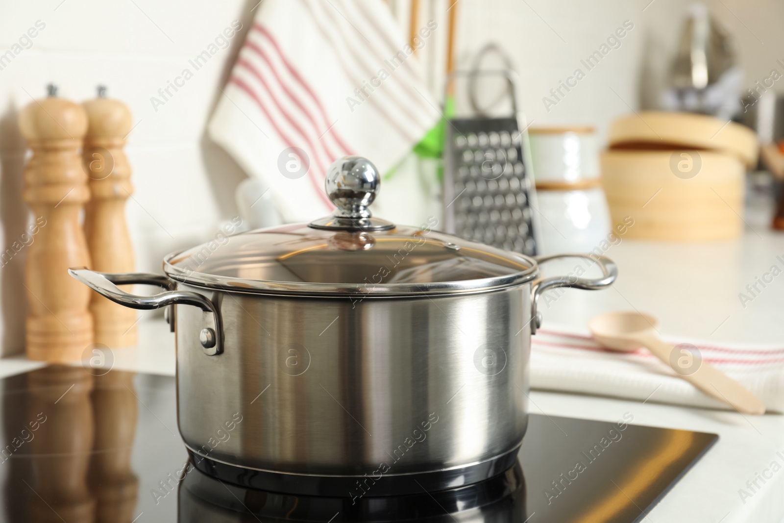 Photo of Shiny pot on electric stove in kitchen. Cooking utensil