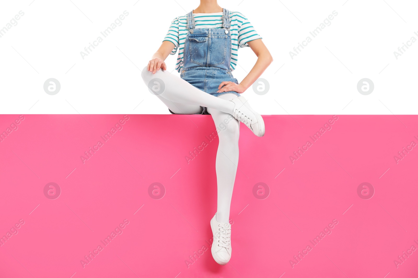 Photo of Woman wearing white tights and stylish shoes sitting on color background, closeup