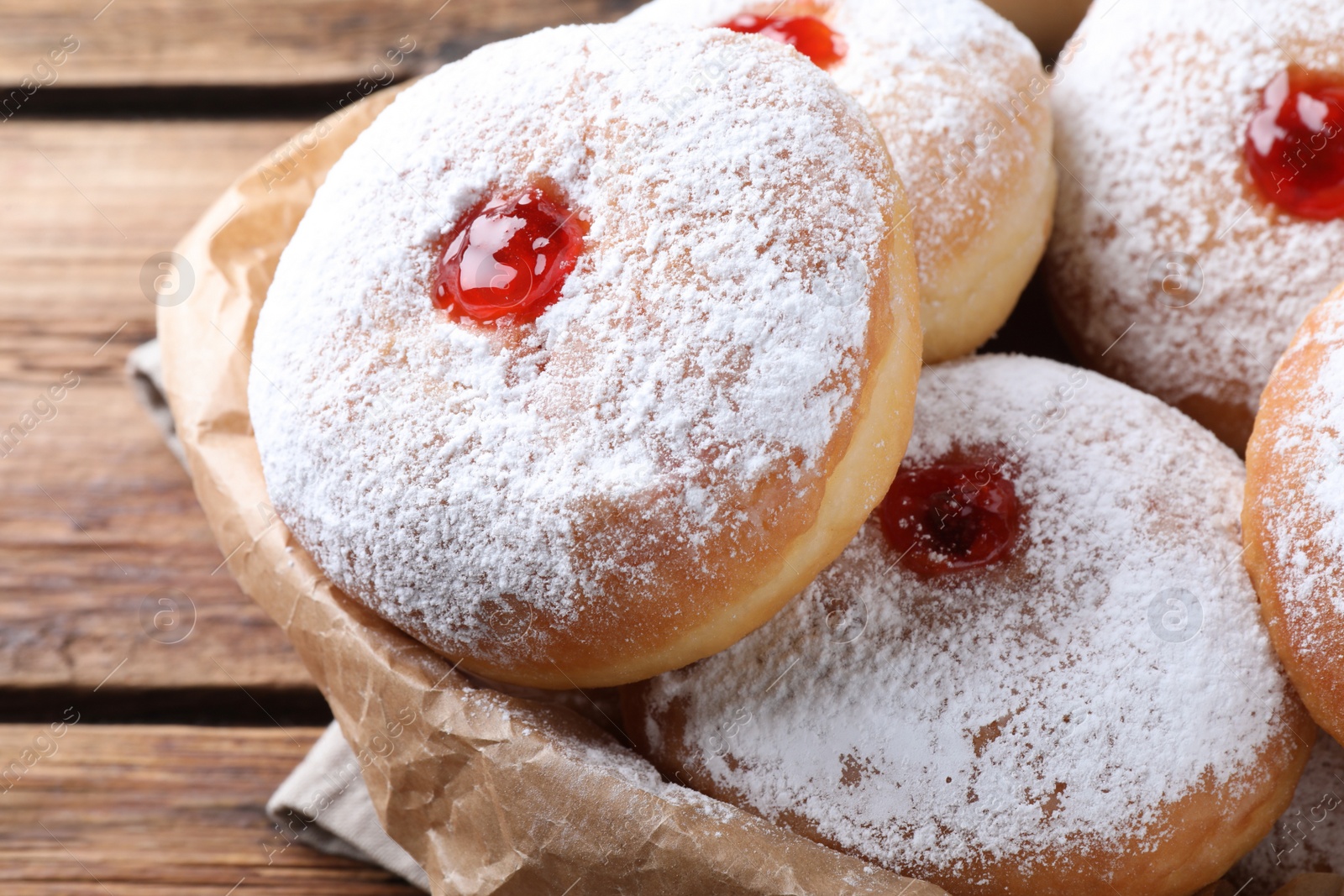 Photo of Delicious donuts with jelly and powdered sugar on wooden table, closeup