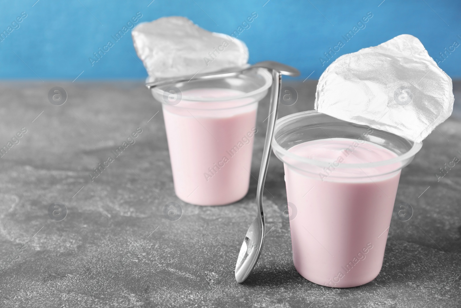 Photo of Plastic cups with tasty yogurt on grey table