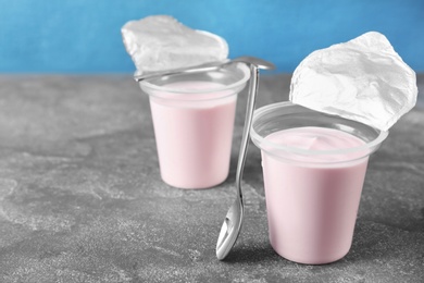 Plastic cups with tasty yogurt on grey table