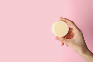 Photo of Woman holding solid shampoo bar against pink background, closeup. Space for text