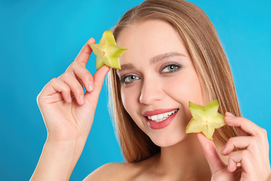 Photo of Young woman with cut carambola on blue background. Vitamin rich food