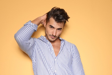 Young man with trendy hairstyle posing on color background