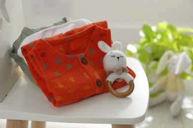 Photo of Baby clothes and toy on chair indoors, closeup