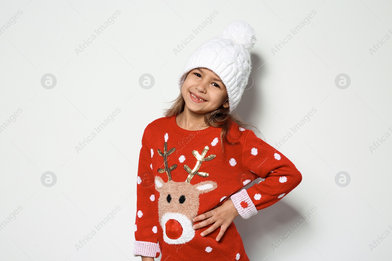 Photo of Cute little girl in Christmas sweater and knitted hat on white background