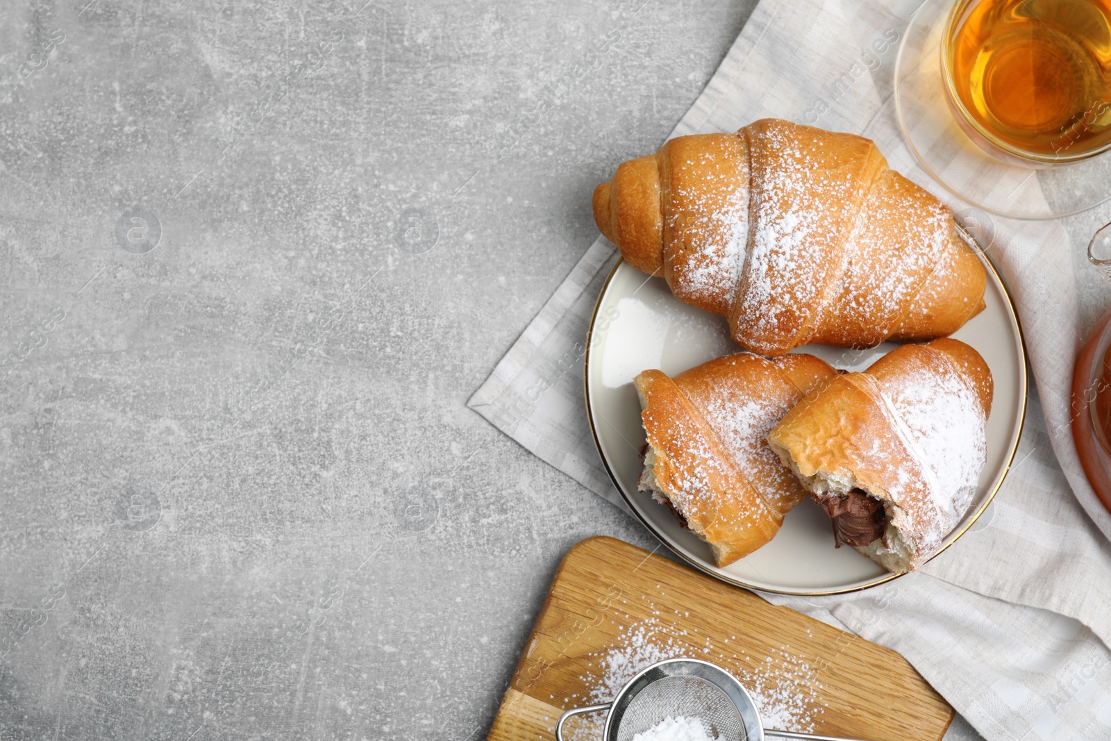 Photo of Flat lay composition with tasty croissants, tea and sugar powder on light grey table. Space for text