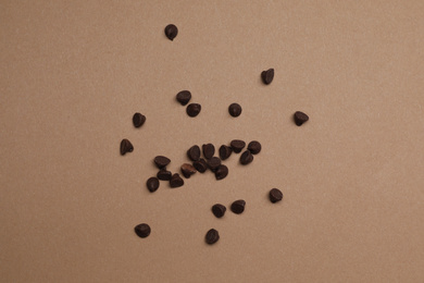 Delicious chocolate chips on brown background, top view