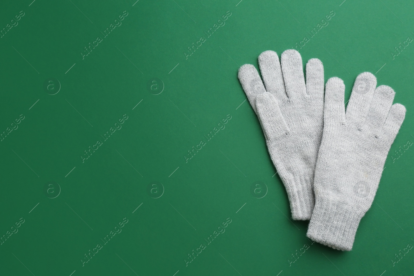Photo of Pair of stylish woolen gloves on green background, flat lay. Space for text