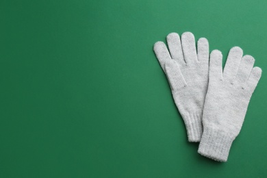 Pair of stylish woolen gloves on green background, flat lay. Space for text