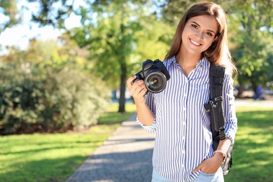 Photo of Young female photographer with professional camera in park. Space for text