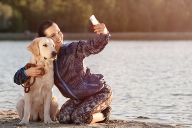 Photo of Young woman taking selfie with together her dog on beach. Pet care