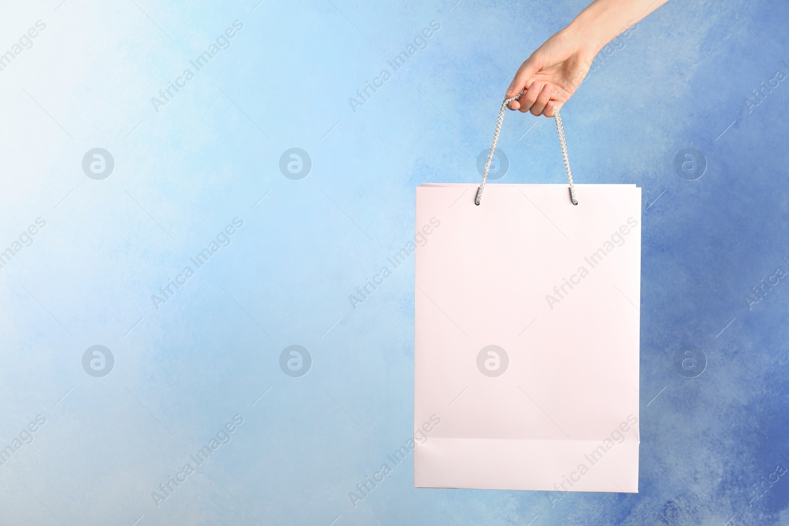 Photo of Woman holding paper shopping bag on color background